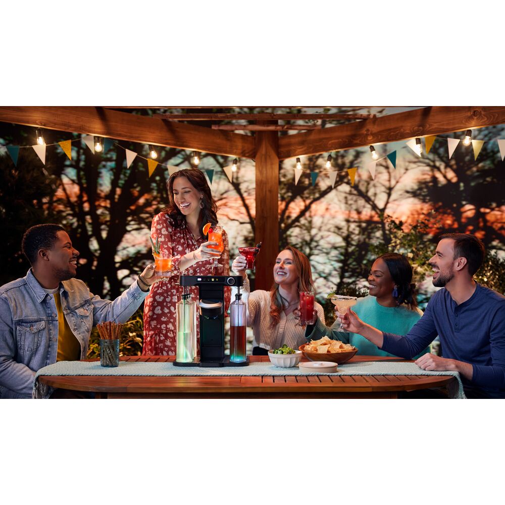 a group of friends sitting on the back patio under a pergola cheersing with their drinks made by the bev by BLACK+DECKER™ cordless cocktail maker