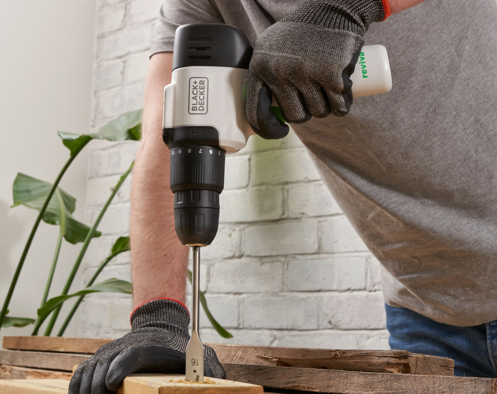 Man using reviva drill to put a hole in a plank of wood.