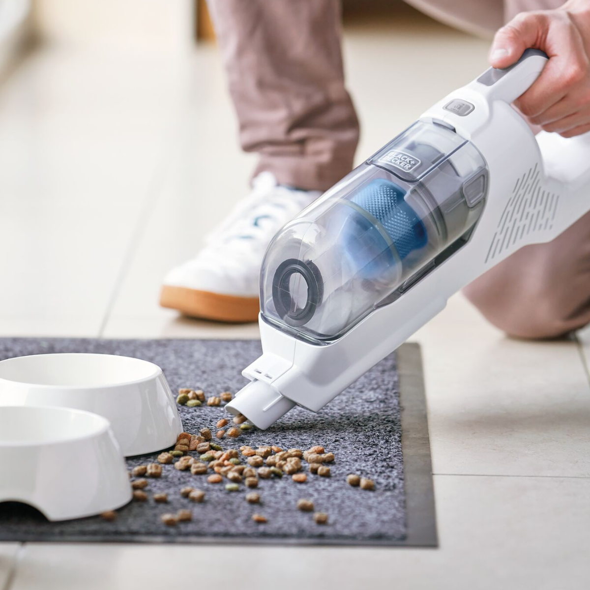 close up of hand vacuum function cleaning up dog food next to dog bowls