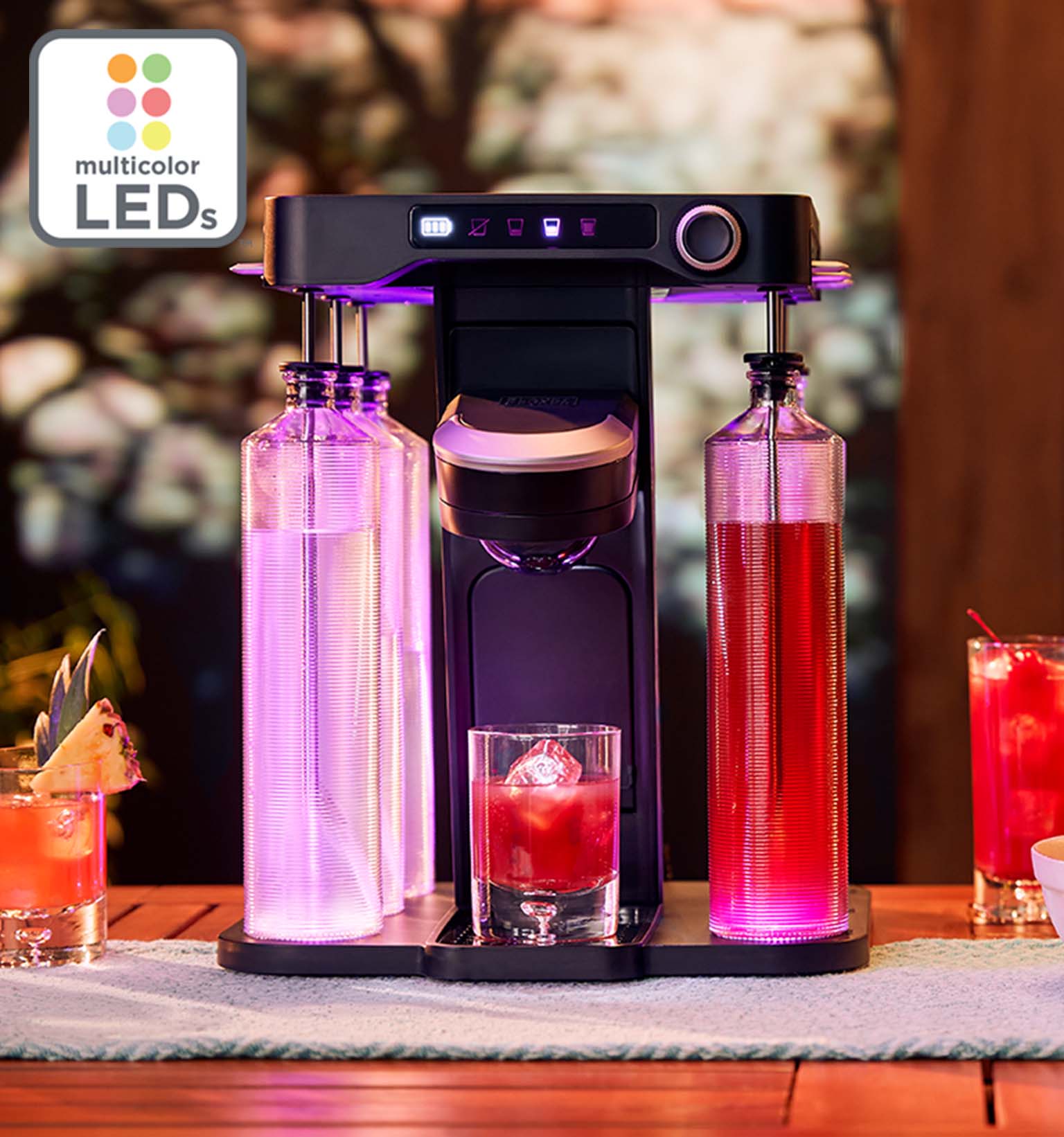 pink lights illuminated on the bev by BLACK+DECKER™ cordless cocktail maker sitting on a wooden patio table with drinks