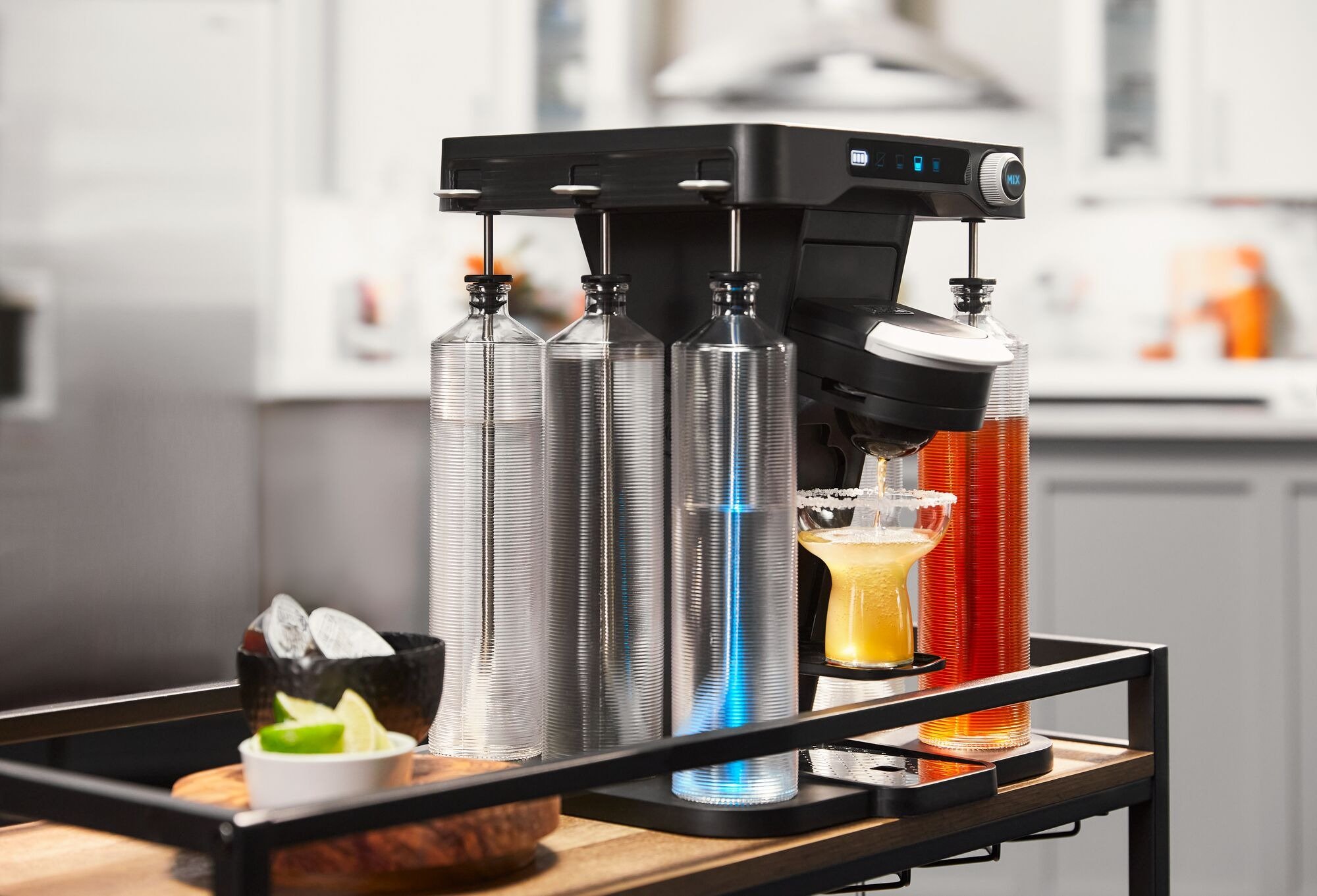 the bev by BLACK+DECKER™ cordless cocktail maker on a bar cart brewing a mango margarita
