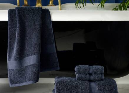 navy towels draped in a pile and draped over a bath