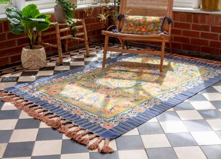 boho style rug on a checker tiled floor, rug has orange tassels