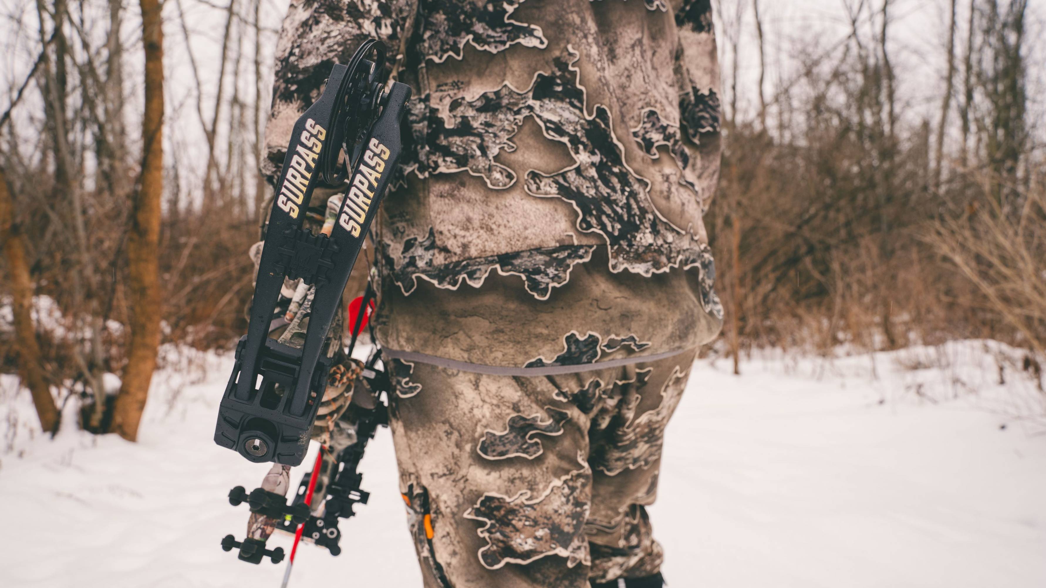 An individual holding a Bear Archery Surpass Compound Bow in the snow