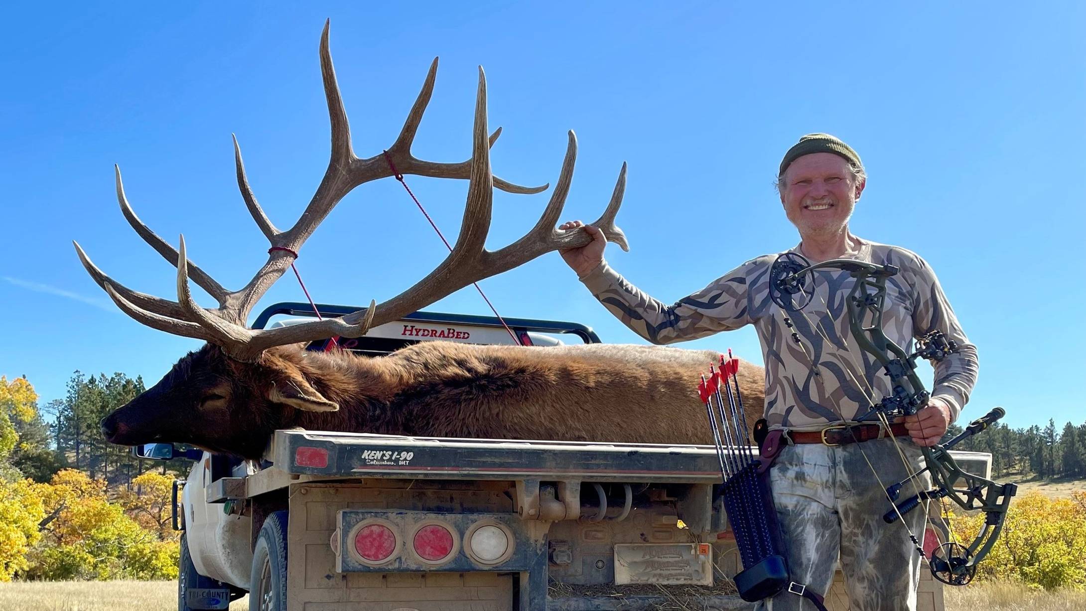 Chuck Adams with Bear Archery Alaskan XT compound bow standing with an elk. 