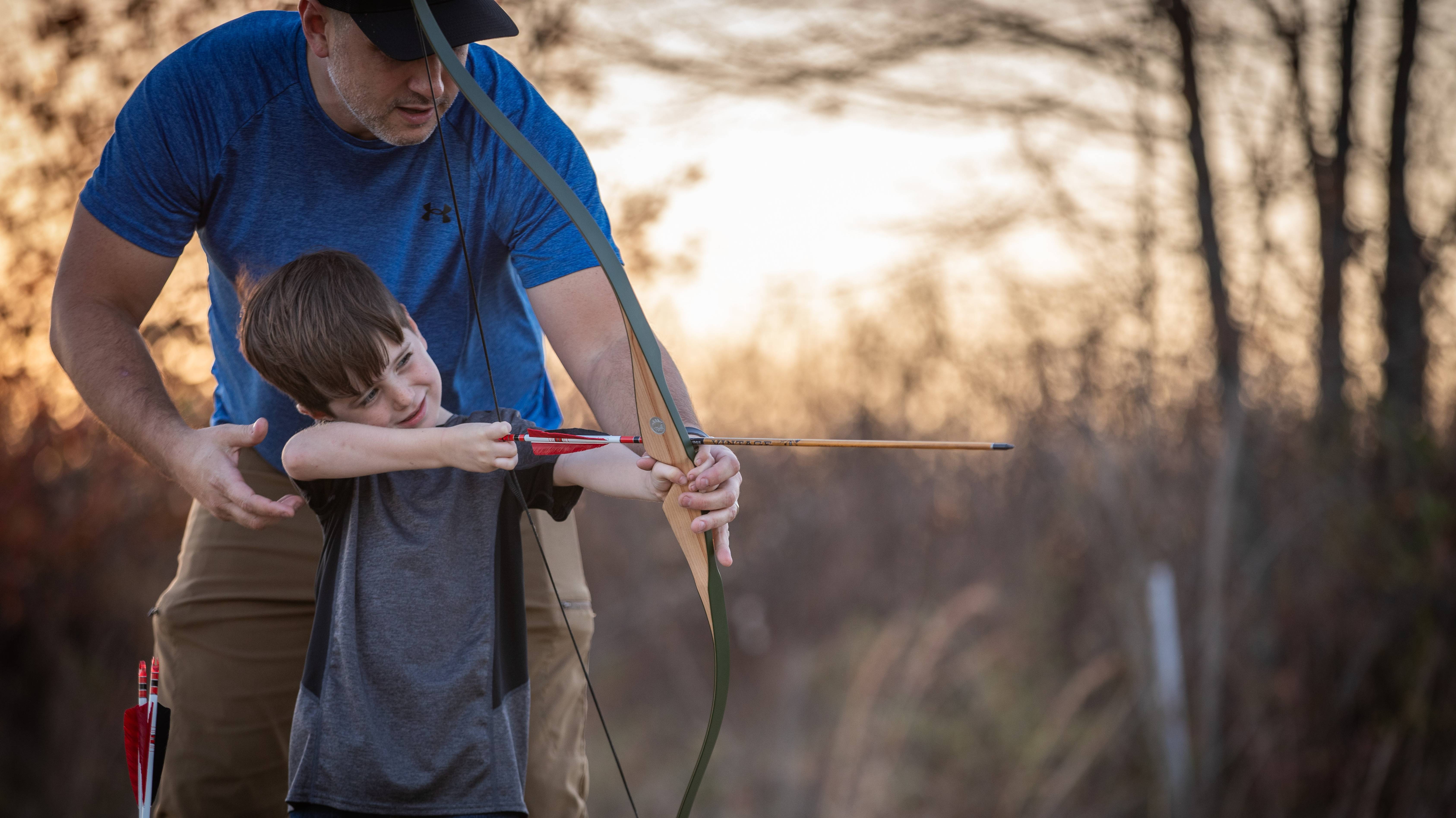 Dad helping son shoot a Bear Archery Little Bear Recurve Bow