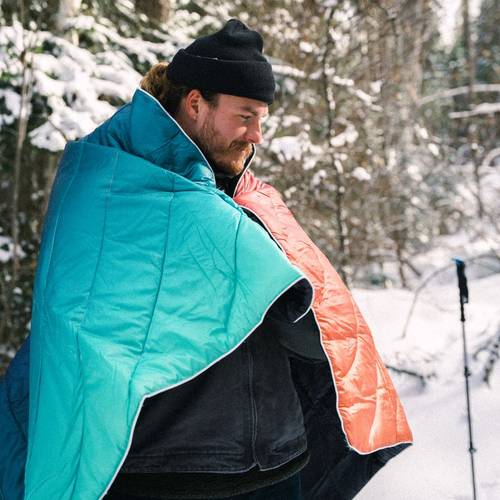 A man snuggled up with his Rumpl fades blanket while out in the snow.
