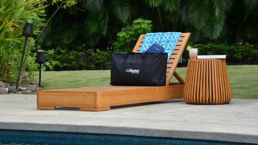 Celluma device and premium padded tote bag shown on a reclining chair at a vacation home with a drink next to the table. Image illustrates the lightweight, highly portable nature of Celluma single-panel devices that are travel-ready and fit easily into one's lifestyle.