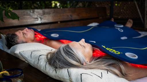 Women and man laying under the Celluma DELUX & DELUX XL devices getting a full body LED red light therapy treatment on pain mode.