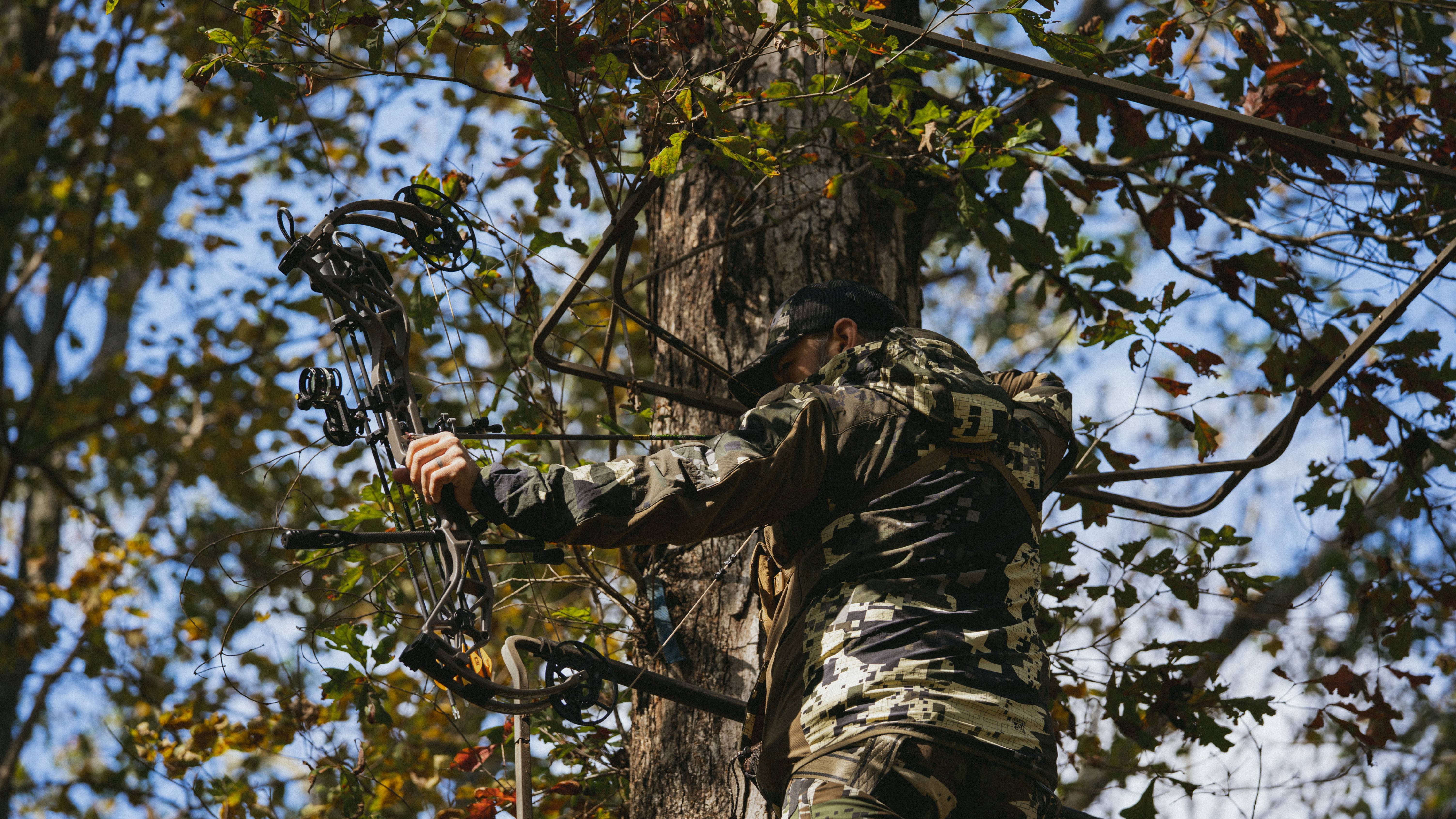 Man shooting the Alaskan Pro RTH compound bow from Bear Archery out of a tree stand.