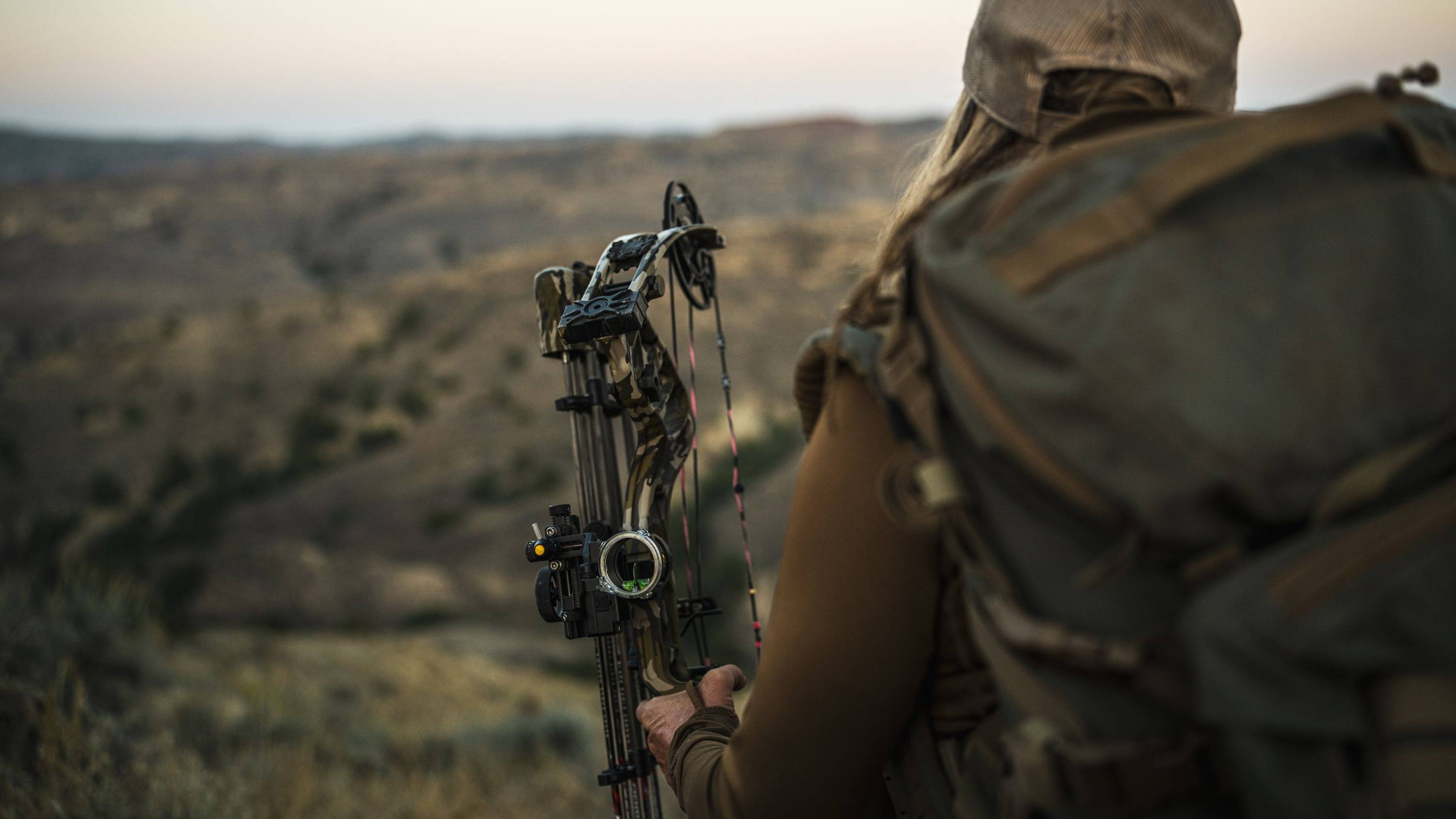 Close up of a woman holding the Resilient RTH short draw compound bow from Bear Archery on a mountain.