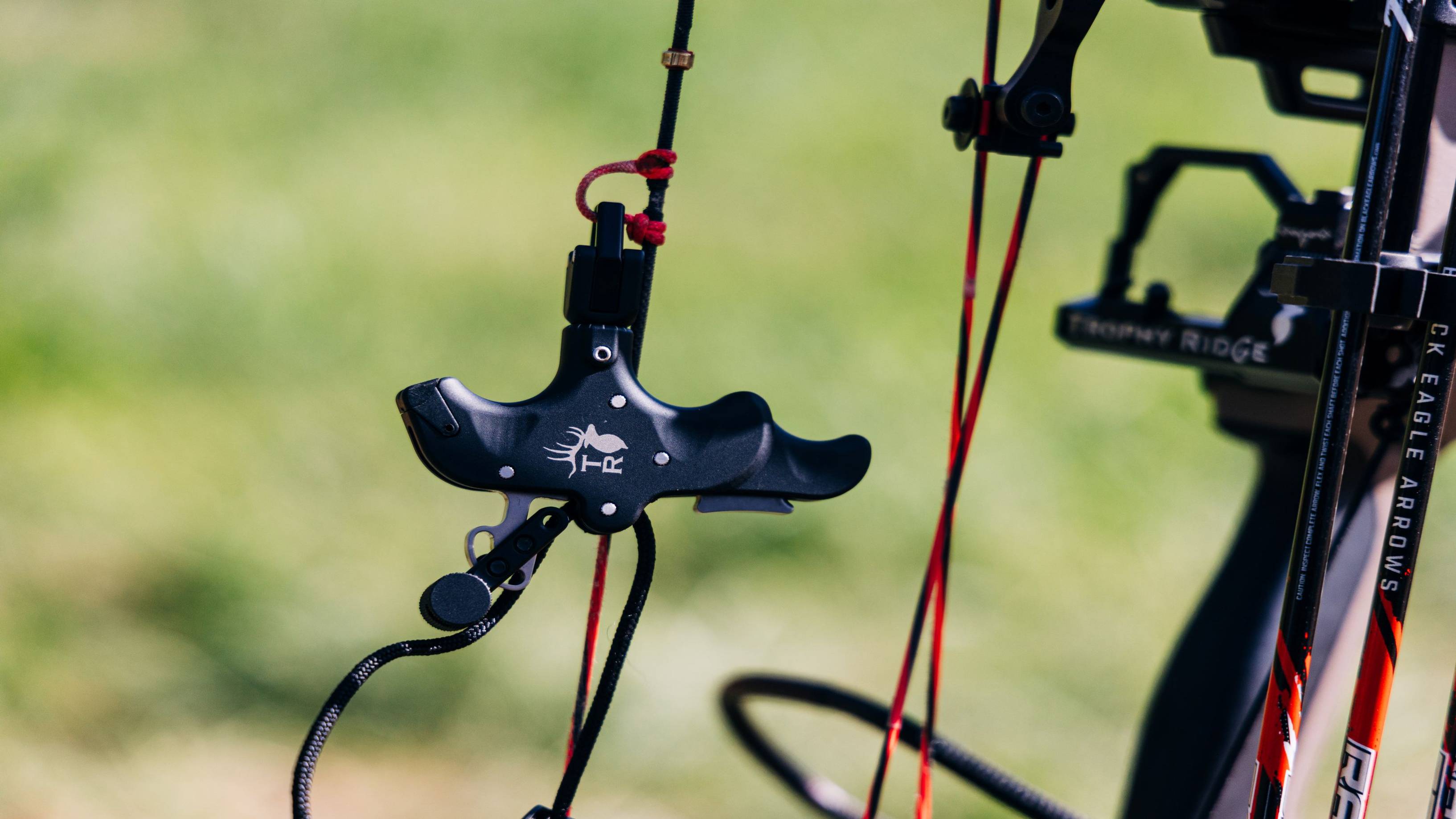 Close up of 3 Finger Precise Pro trigger release hanging from d-loop on compound bow.