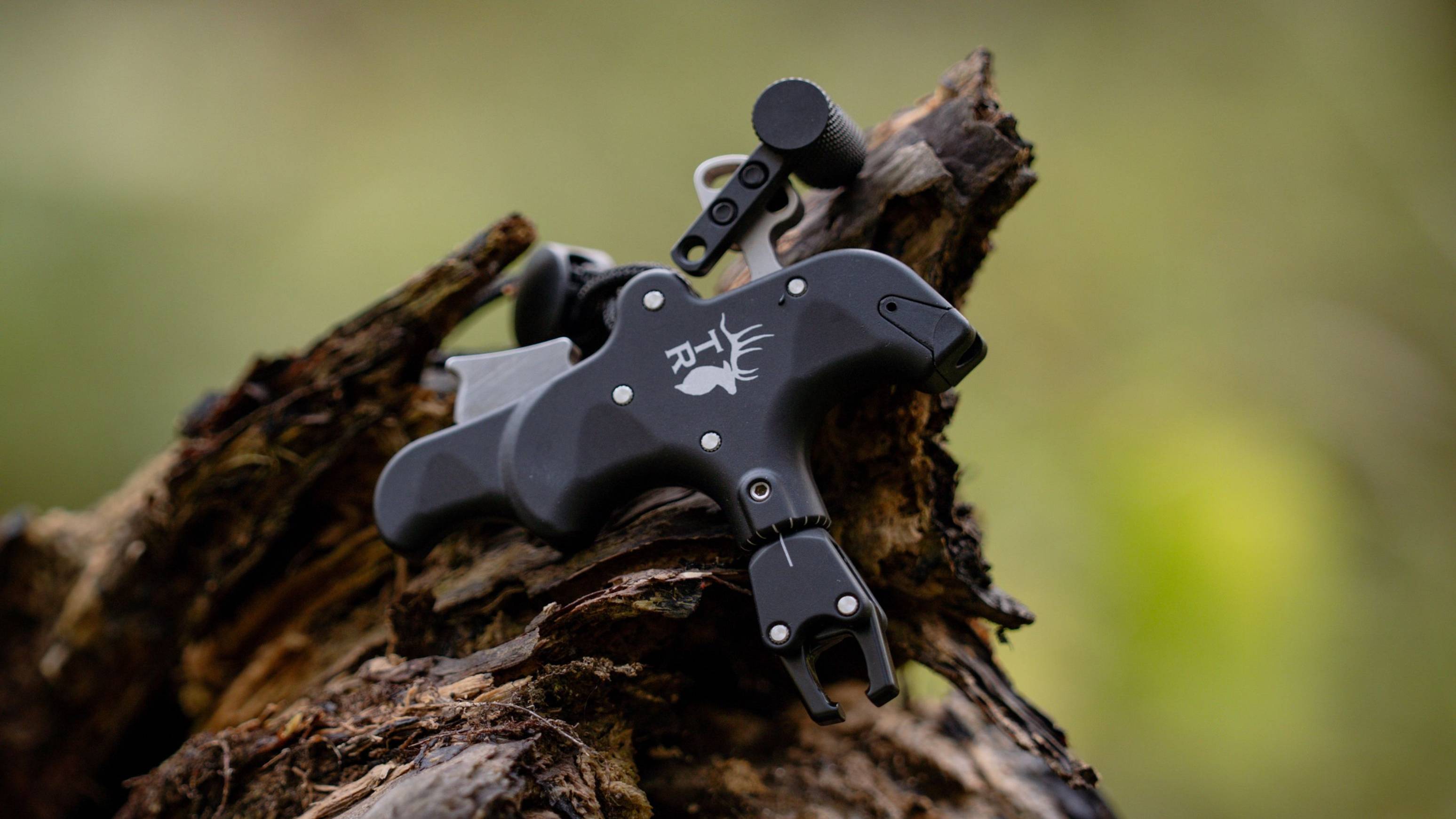 Close up of 3 Finger Precise Pro thumb trigger release from Trophy Ridge laying on a log.