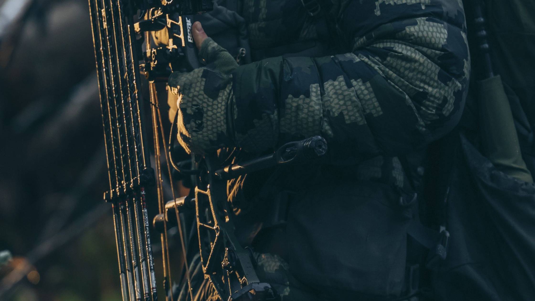 Person in hunting gear with compound bow equipped with Seismic Stabilizer from Trophy Ridge