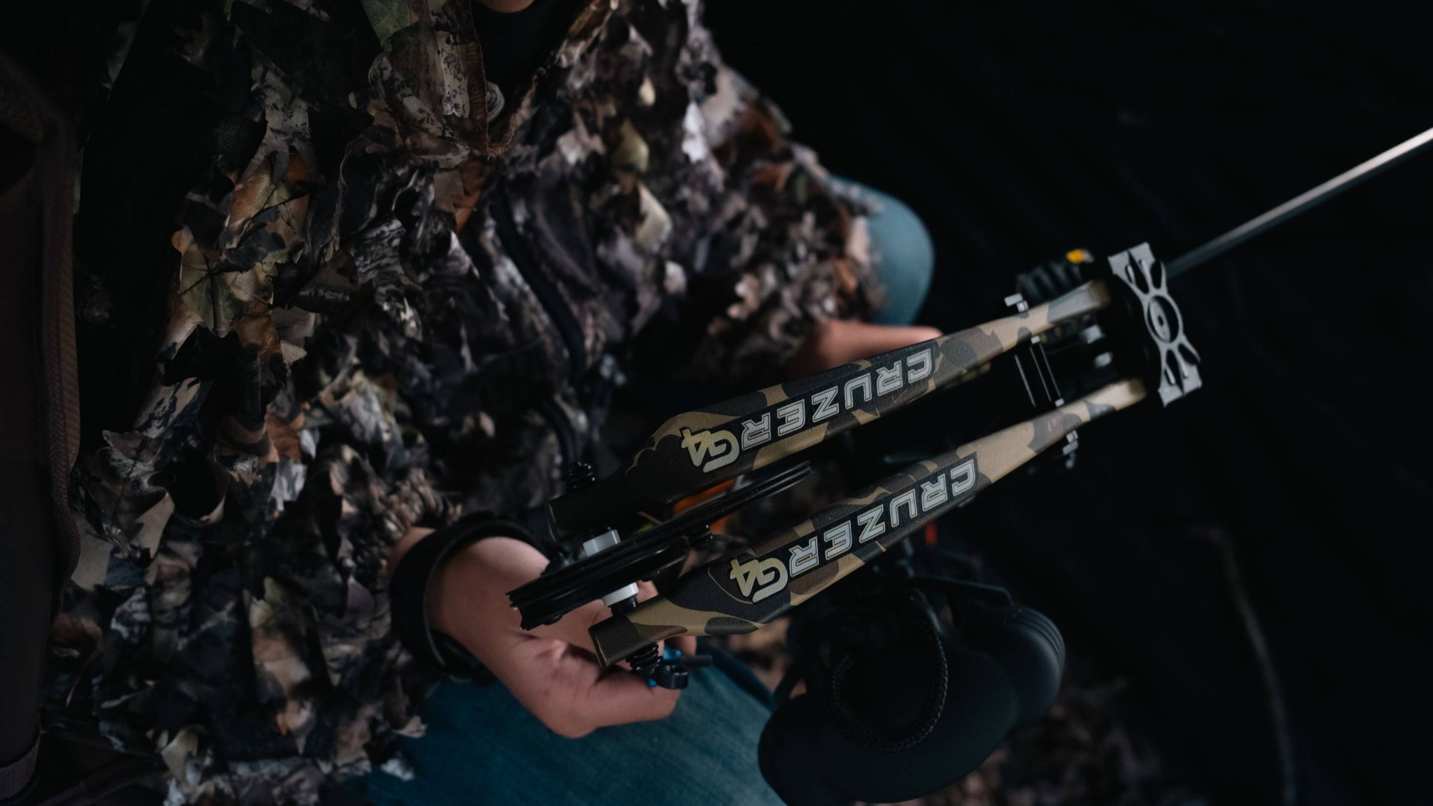 Person in hunting blind with the Bear Archery Cruzer G4 compact compound bow.