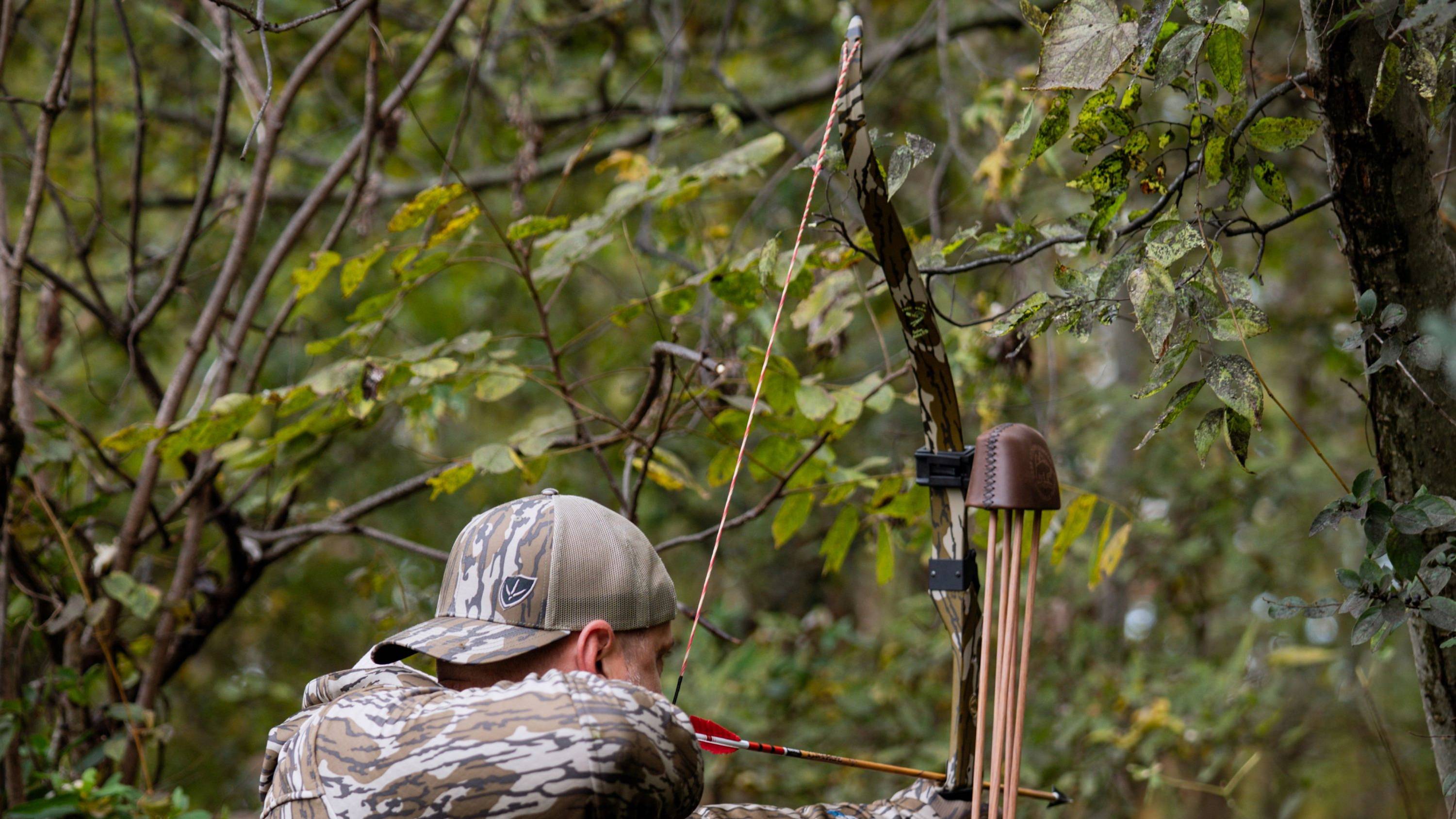 Man shooting a takedown recurve bow with Mossy Oak Bottomland Camo Take Down Bow Limbs from Bear Archery.