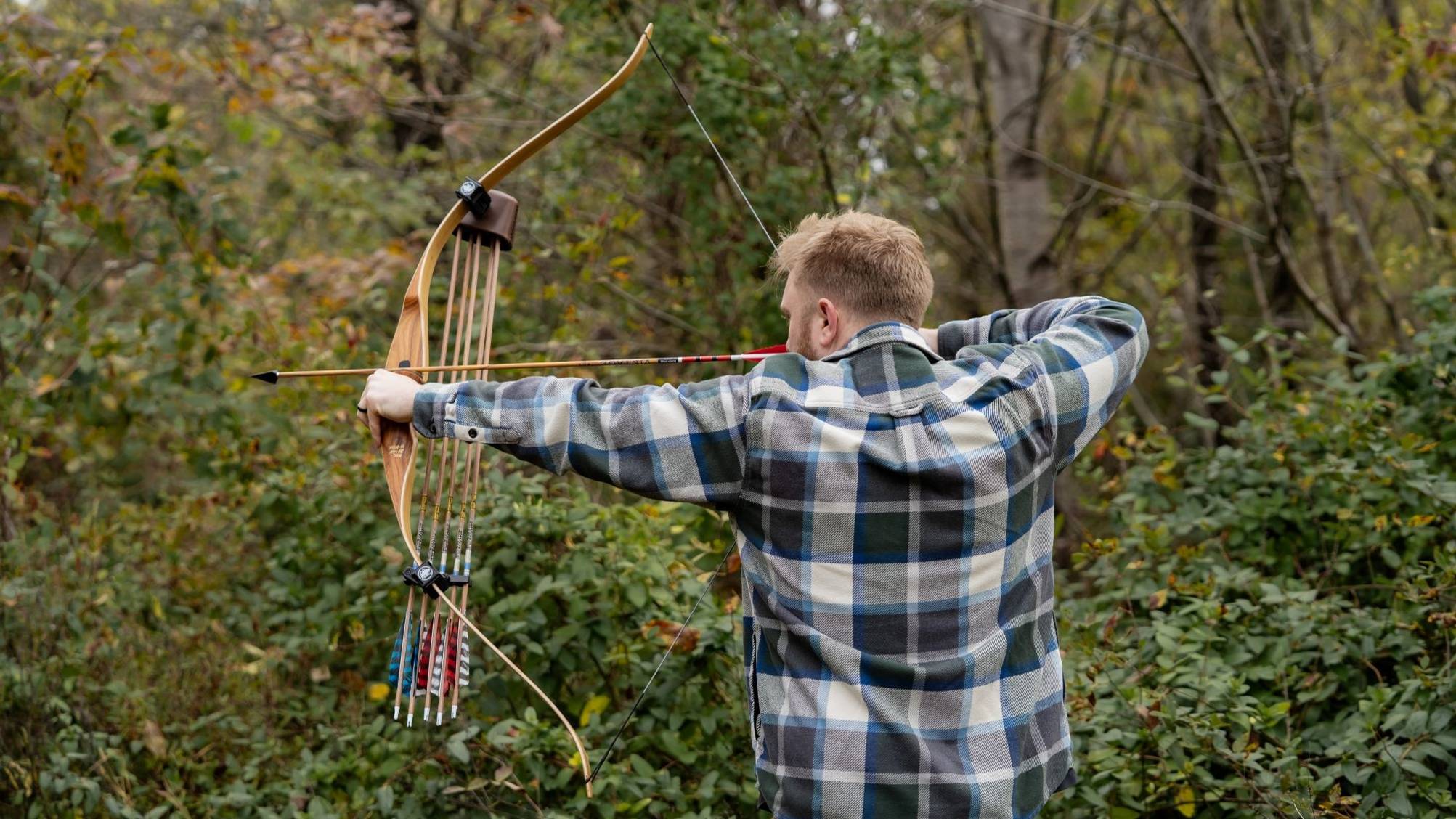 Man at full draw shooting the Grizzly Hunter Hybrid Longbow from Bear Archery.