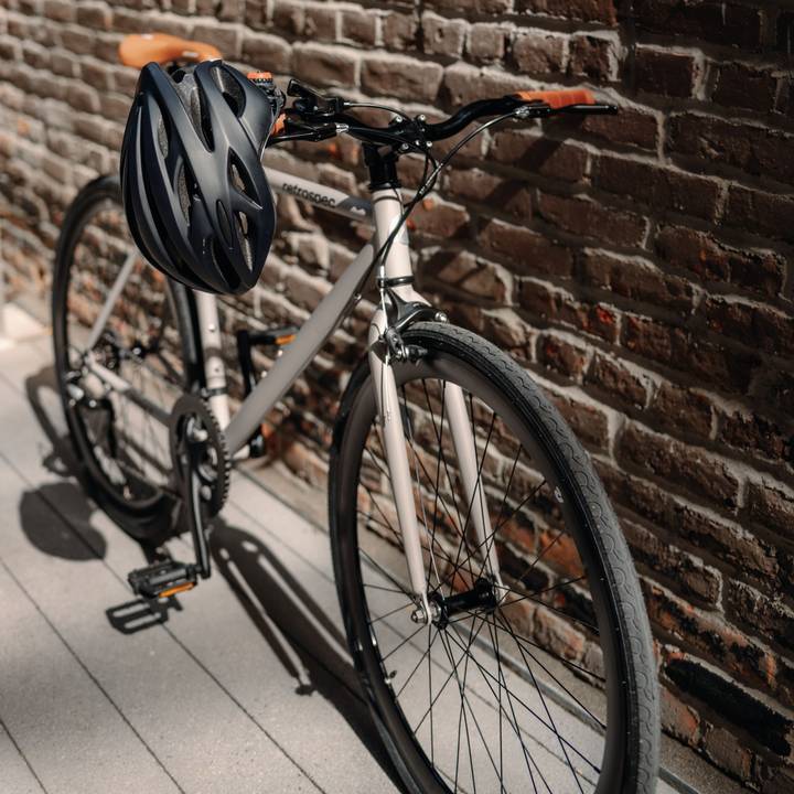 A bike leaning against a brick wall with a Silas Bike Helmet resting on the handlebar.
