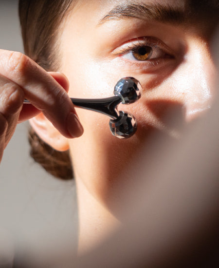Woman Using Sculpting Facial Roller Across Cheek Bone