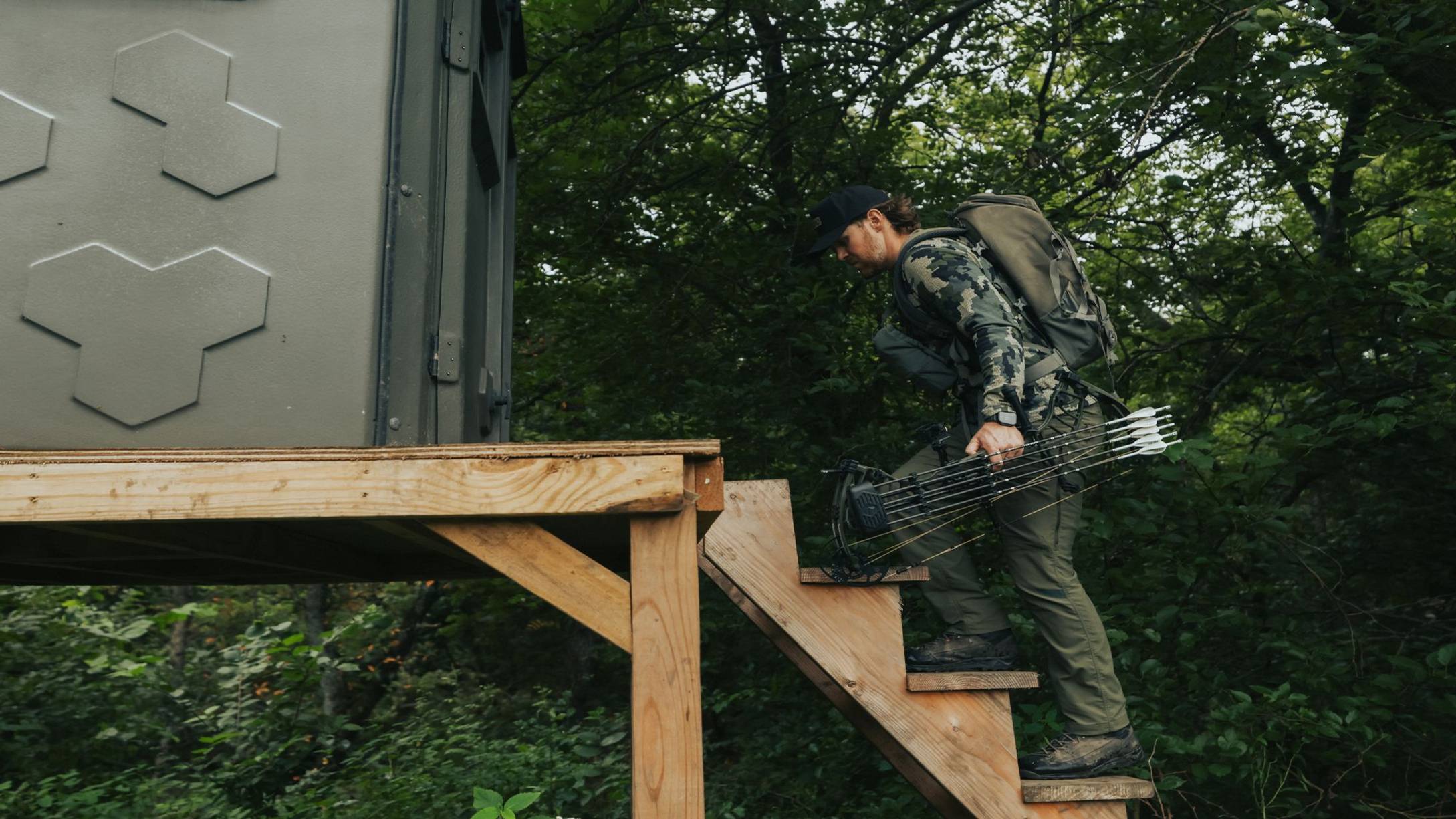 Man walking into a blind with the Warrant RTH compound bow from Bear Archery.