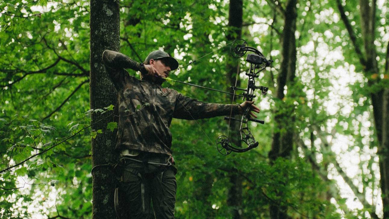 Man hunting in a tree stand drawing the Paradigm Pro compound bow from Bear Archery