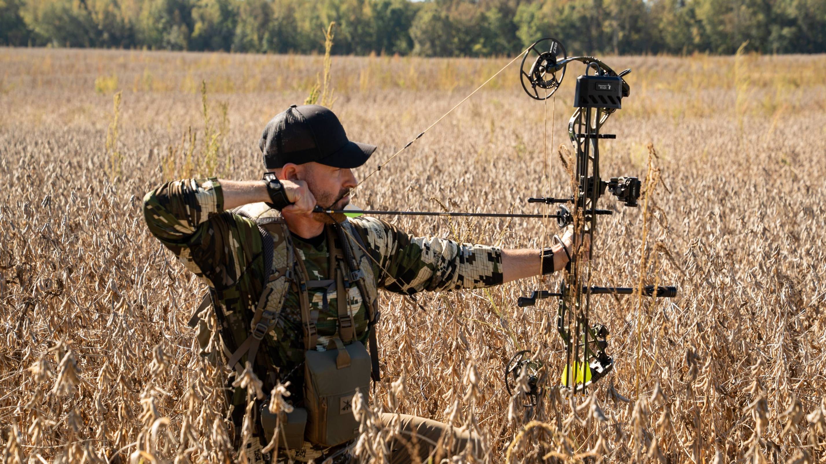 Man holding the Source compound bow from Bear Archery at full draw in a field.