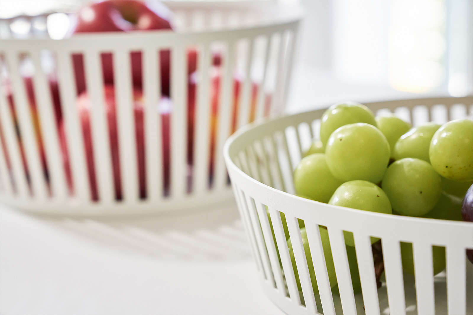 Side view of Yamazaki Home White fruit basket holding fruits. 