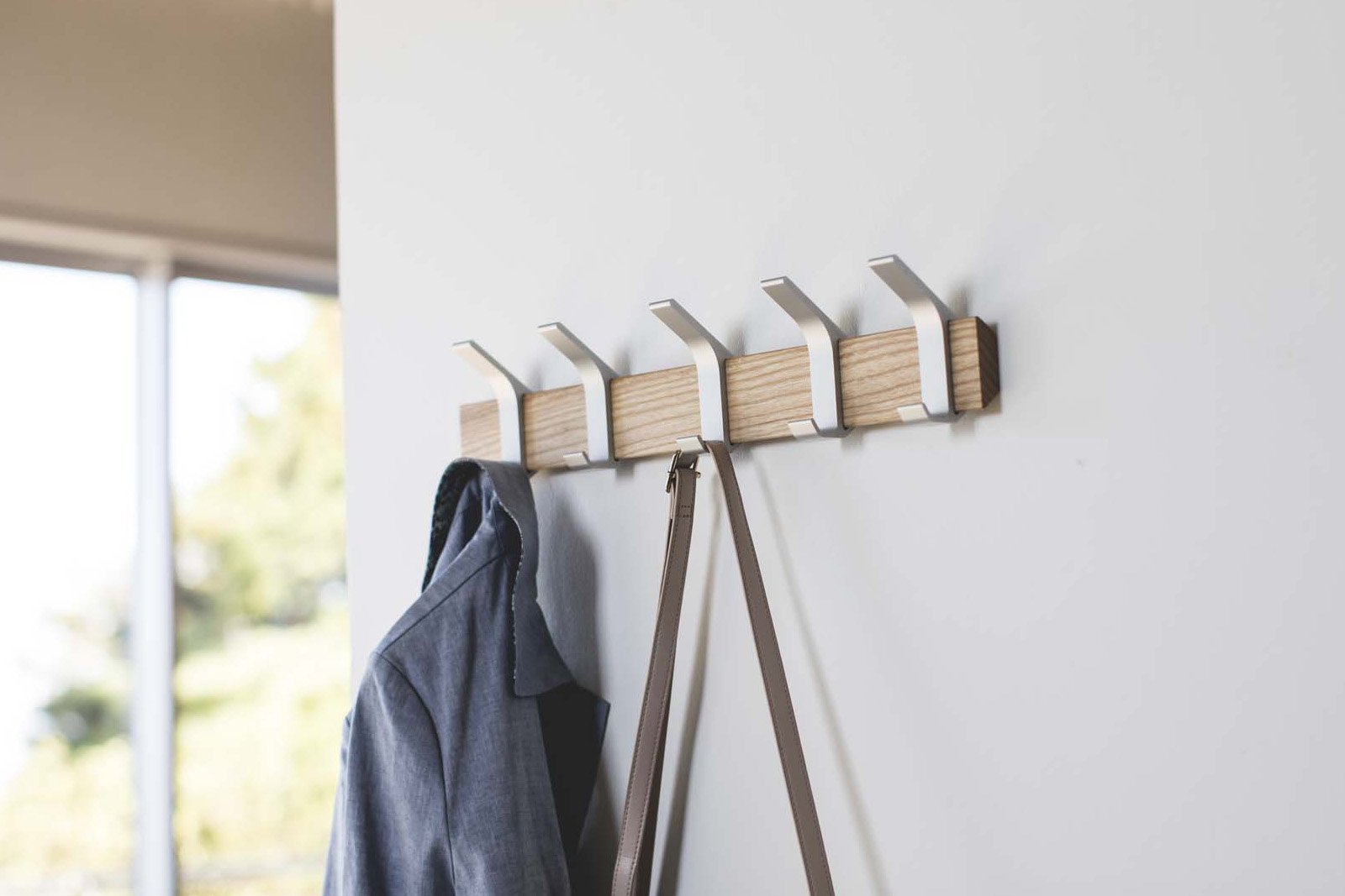 Yamazaki Home Wall-Mounted Coat Hanger holding a bag and a jacket on the wall. 