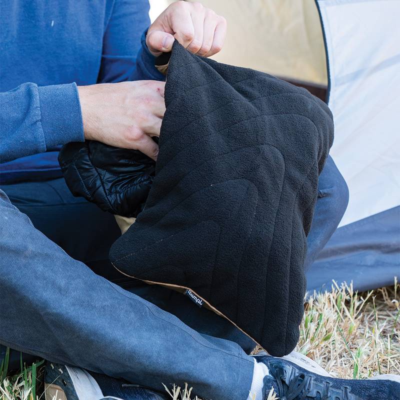 Person stuffs their down puffy jacket into the Rumpl Stuffable Pillowcase which now doubles as storage and a makeshift camp pillow.