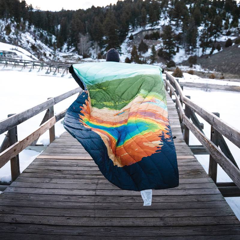 Rumpl National Park Blanket billowing in the wind so the print is seen as a person holds it out behind them.