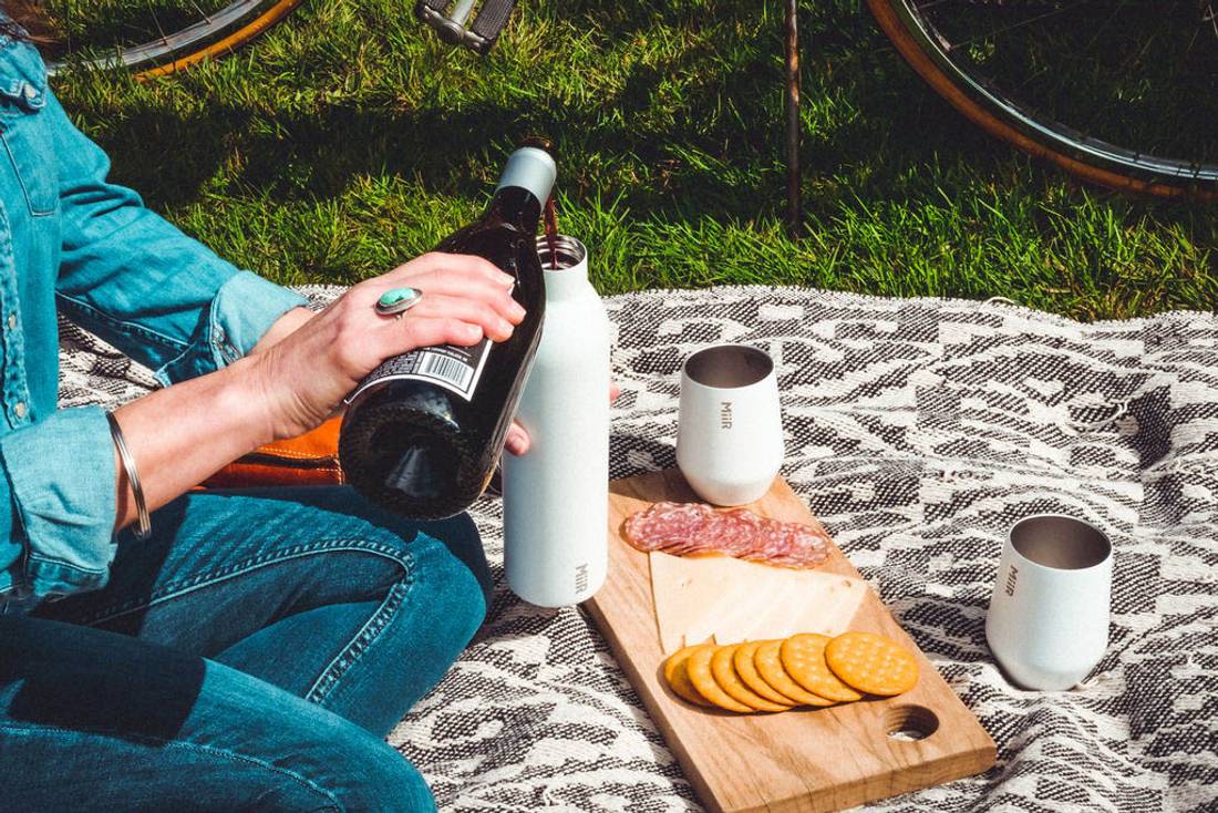 Person having a picnic with MiiR Wine Tumbler and MiiR Wine Bottle in white.