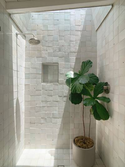clé tile terracotta eastern elements rice paper 4x4 tile installed all over the serene white shower walls and floor with a sky light above.