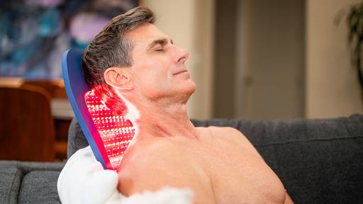 Man enjoying the Celluma SPORT for pain on the back which sitting on the couch at home.