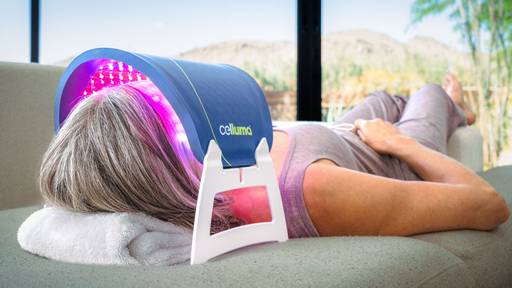 Women on couch using Celluma FACE on aging mode. 