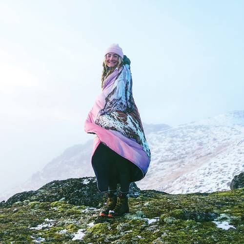 Rachel Pohl looking extra comfy and cheery wrapped in the Original Puffy Blanket - Matterhorn. 