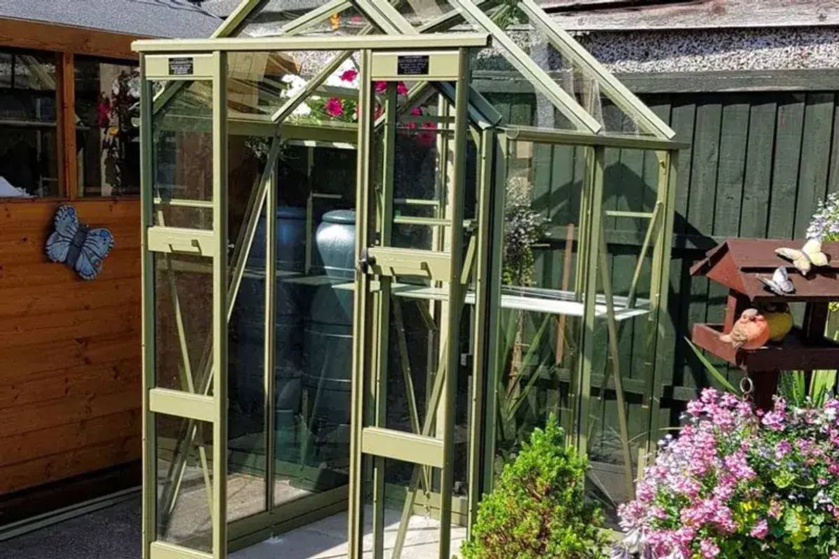 Compact 4x4 greenhouse next to shed