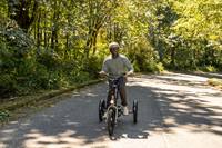 Man riding the RadTrike electric tricycle with trees in the background.