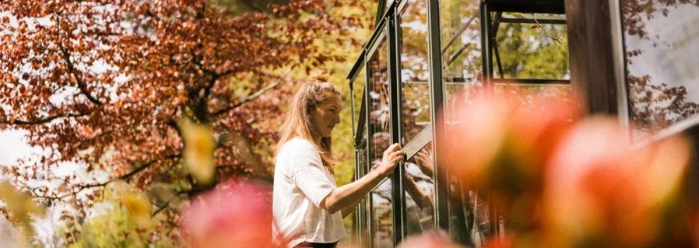 Lady opening her greenhouse doors on an autumnal day