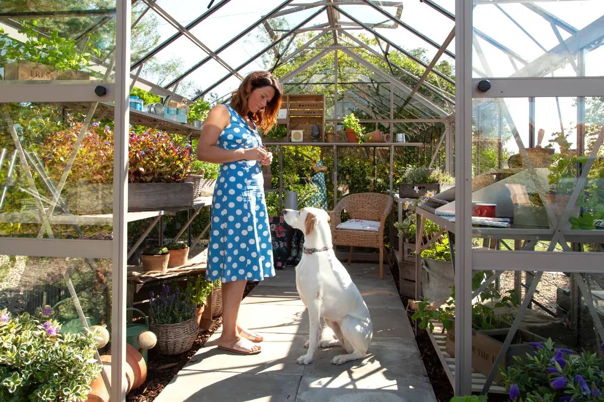 Lady and her dog in a well stocked greenhouse