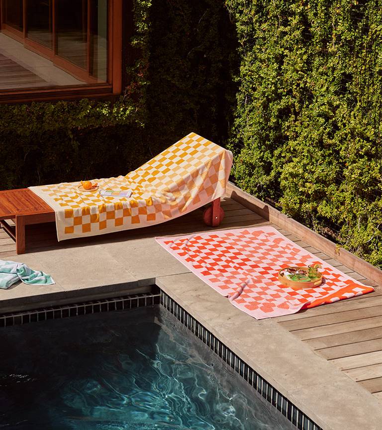 Poolside scene featuring our latest checkerboard towel collection in Mango and Pop Pink.