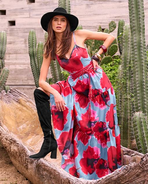 Model is wearing blue and red floral maxi dress with black boots and black hat.