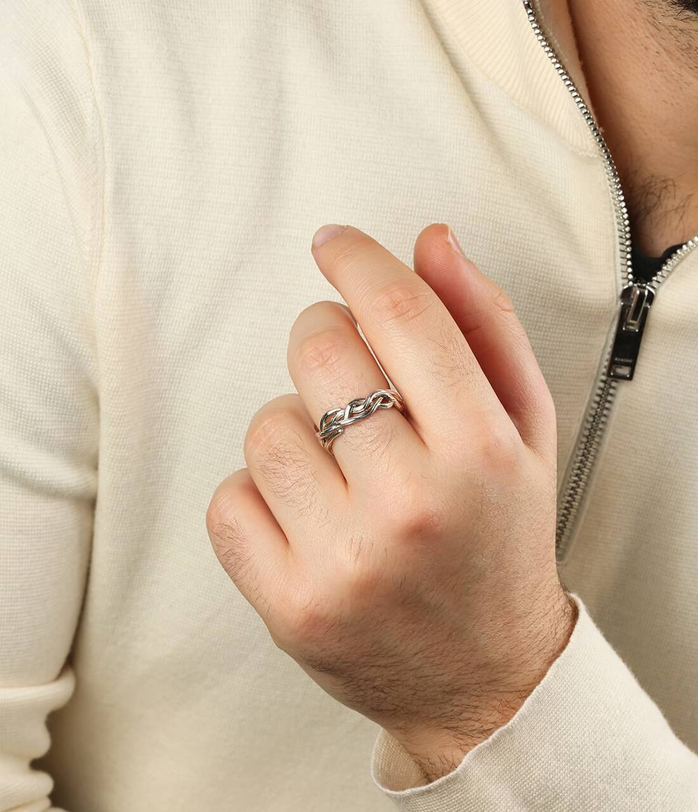 A man in a white jumper wears a silver ring that is a reminiscent of vines that grow in the enchanted forest.