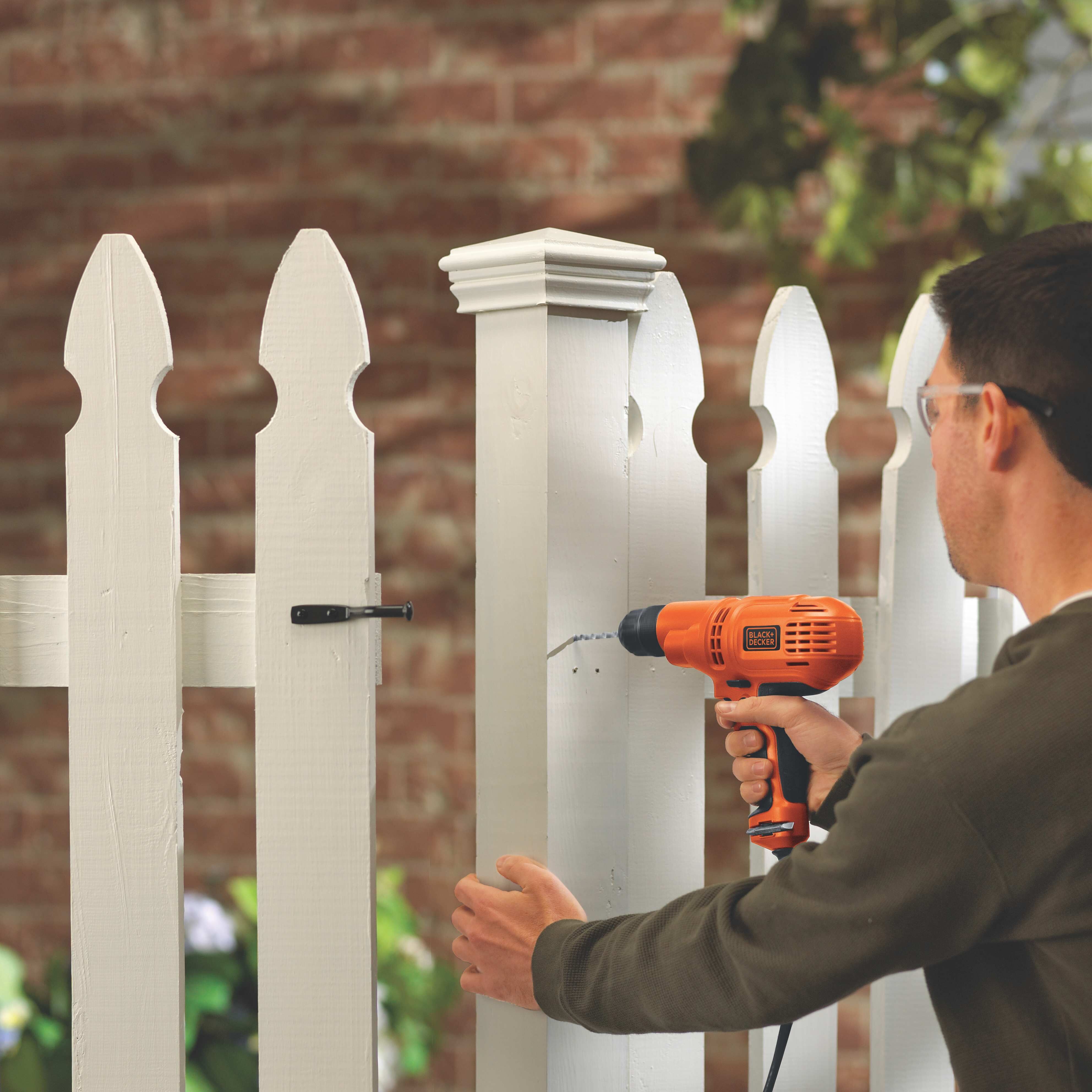 Man using drill on a fence