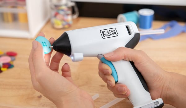 close-up of a BLACK+DECKER cordless glue gun being used to add glue to a decorative button