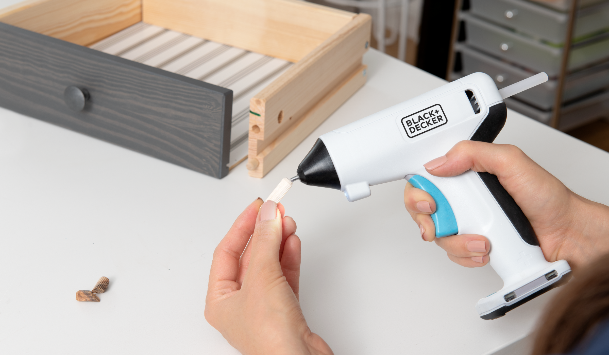 Person using BLACK+DECKER crafting cordless glue gun on a broken drawer