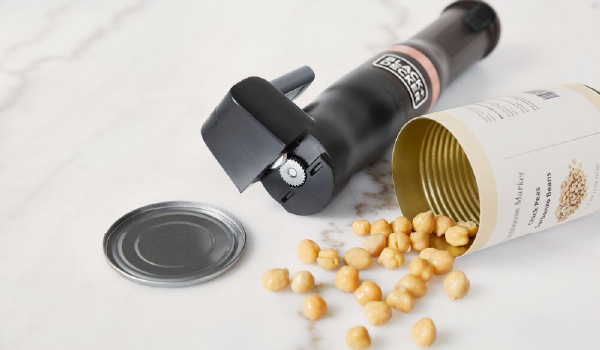 Can of opened chickpeas lying next to the grey. BLACK+DECKER kitchen wand can opener