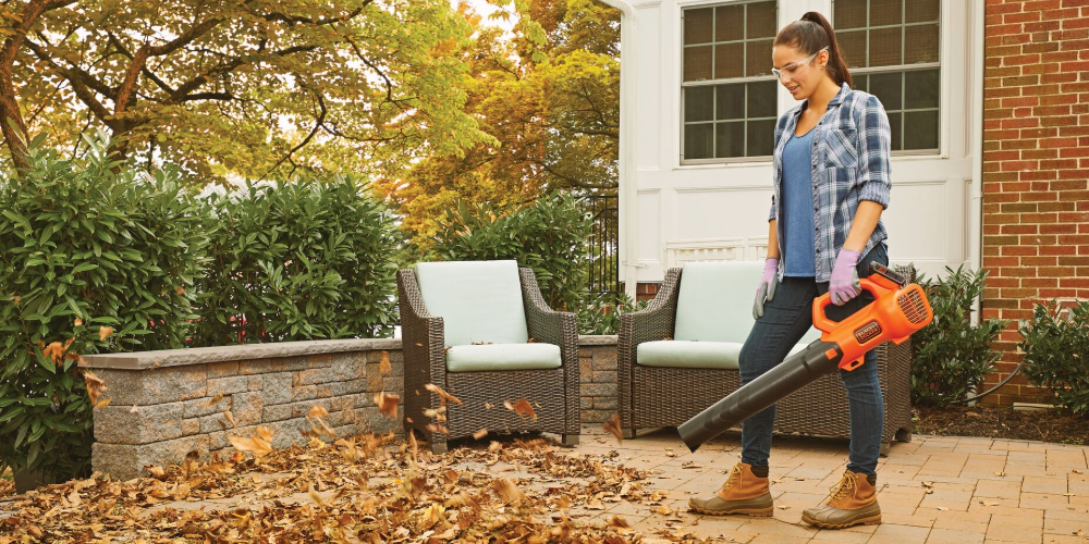 Woman using leaf blower outside