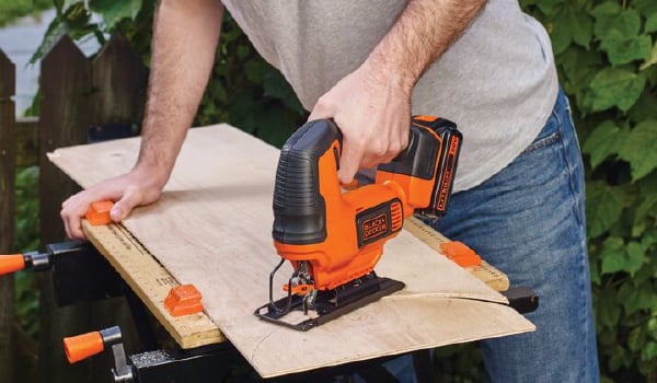 20 volt MAX cordless jigsaw being used by a person to cut wood outdoors.