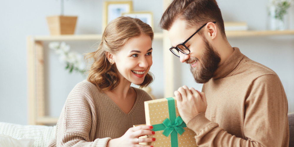 man and woman exchanging presents in a living room