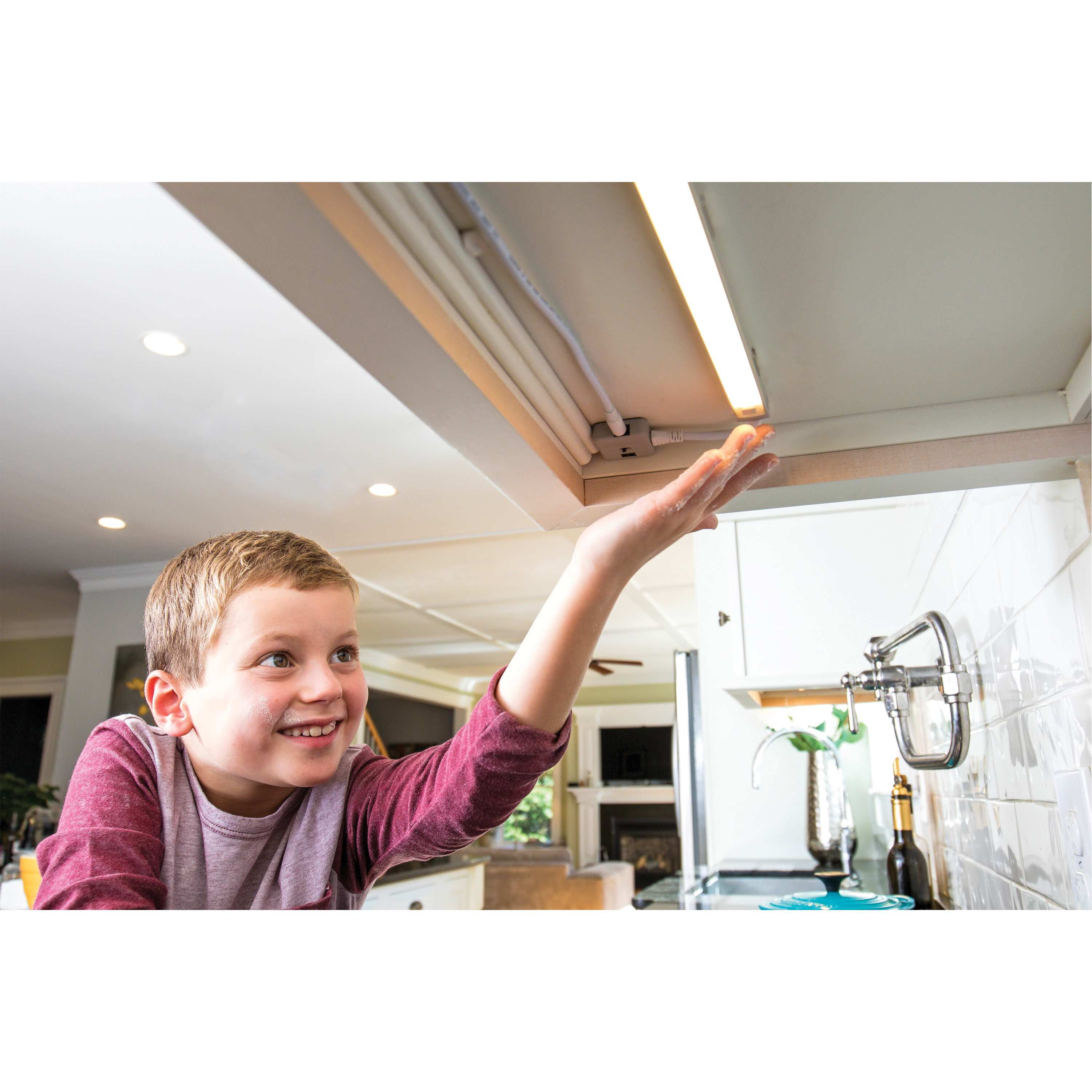 Child turning on a light under a cabinet